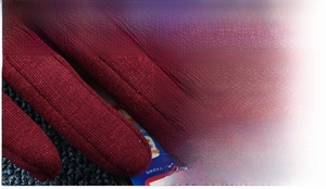 Detailed macro view of the reinforced fingertip stitching on a red winter knit glove