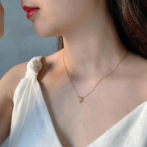 Close-up of minimalist gold star pendant necklace with sparkling cubic zirconia on model