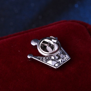 Macro shot of silver crown lapel pin on red velvet background showing butterfly clutch back