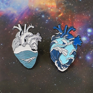 Artistic wave and calm sea anatomical heart enamel pins on a starry background