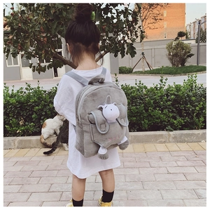 Close-up of a grey plush children's backpack featuring a cute white unicorn doll
