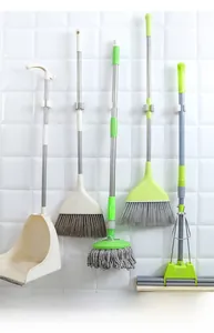 Wall-mounted mop and broom holder organizing cleaning tools on white bathroom tiles