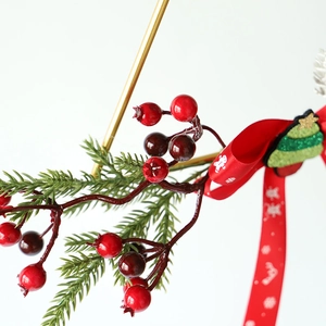 Gros plan de baies de Noël rouges avec aiguilles de pin et ruban à motif pain d'épice