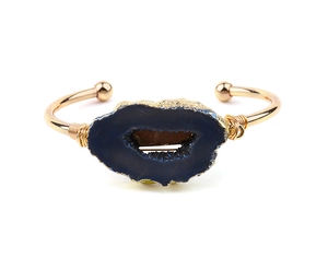 Macro detail of hand-wrapped copper wire and blue druzy geode stone on a gold cuff