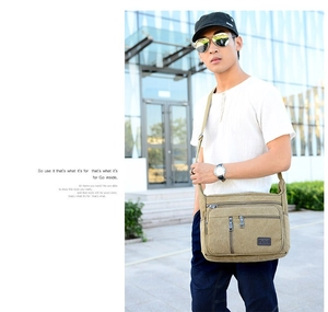 Outdoor shot of khaki canvas shoulder bag with multiple zippered pockets and adjustable strap