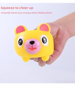 Close-up of hand squeezing a yellow bear squishy stress relief toy made of soft silicone