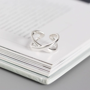 Detailed view of silver crossover ring resting on an open book under natural light