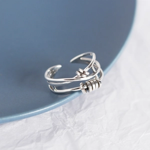 Macro shot of silver multi-layer crossover open ring on a dark blue plate edge