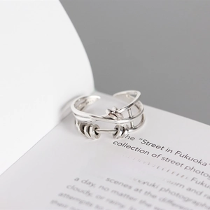 Close-up of S925 sterling silver multi-layer crossover ring with movable beads on a book