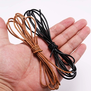 Hand holding round genuine leather cords in black and brown for DIY jewelry making