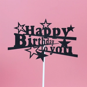 Detail of black glitter Happy Birthday To You cake topper with star patterns on pink backdrop