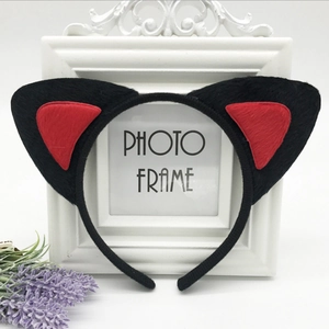 Detail of plush black and red cat ear headband displayed on a white photo frame