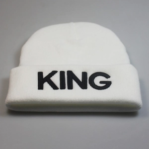 Detailed view of the black KING letter embroidery on the white knitted beanie hat