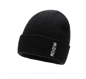 Close-up of black ribbed knit beanie featuring detailed texture and side woven label
