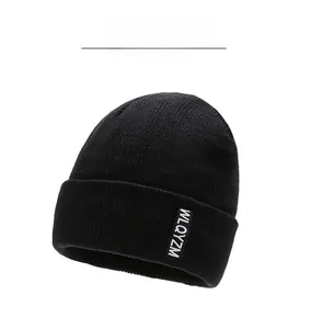Detail of black ribbed knit beanie with a stitched white WLQYZM letter logo patch