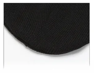 Macro detail of the reinforced crown stitching on a black winter knitted beanie hat