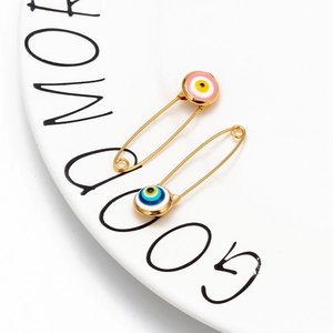 Detailed view of evil eye safety pins in gold finish on a white decorative plate