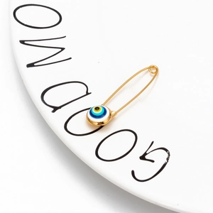 Close-up of a gold evil eye pin brooch on a white plate with Good Morning text