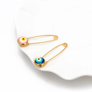 Close-up of pink and blue evil eye safety pins on a white decorative ceramic tray