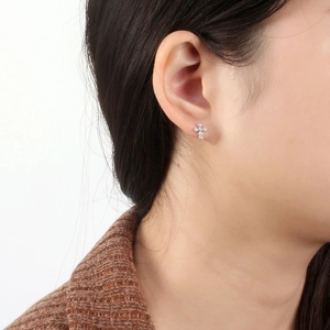 Close-up of a silver cross stud earring with zircon stones worn by a model