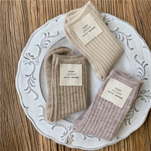 Close-up of three pairs of thick wool blend ribbed socks in beige, brown and pink colors