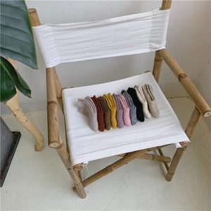 Collection of thick wool knit crew socks in various warm colors on a minimalist chair