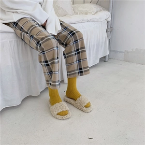Close-up of cozy beige plush slippers paired with yellow wool socks for winter warmth