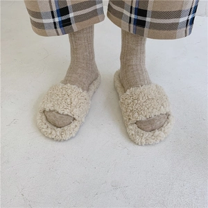 Cozy cream faux fur slide slippers shown on model wearing wool socks and plaid pants