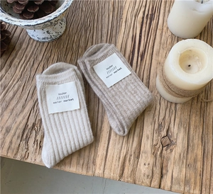 Cozy knit wool socks in beige and khaki colors on a rustic wooden table detail