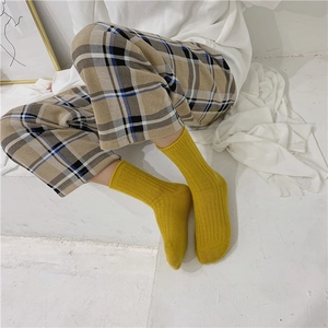 Close-up of yellow ribbed wool socks on model paired with beige checkered trousers