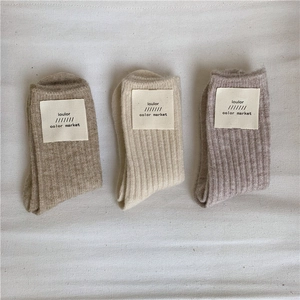 Detailed flat lay of three pairs of ribbed wool blend socks in beige, khaki, and gray-purple