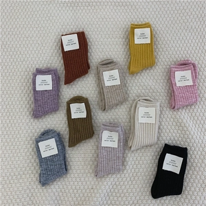 Flat lay view of multi-color thick knitted wool socks with loulou color market labels