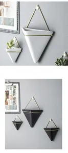 Detail of Nordic wall-mounted geometric ceramic planters with gold metal brackets