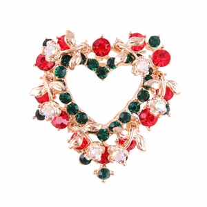 Detail of heart-shaped brooch with red and green crystals on golden base