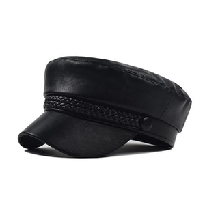 Detail of black leather baker boy hat with braided rope trim and metallic side buttons