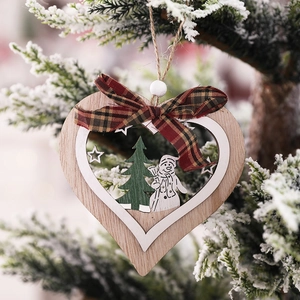 Wooden Christmas heart ornament with snowman and tree hanging on a pine branch