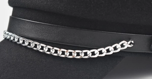 Macro detail of the black wool beret featuring a leather band and silver metal chain link