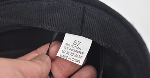 Detail view of cotton blend inner lining and wash label of black chain baker boy hat