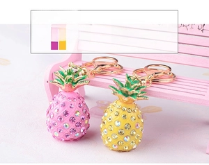 Macro detail of rhinestone pineapple keychains in pink and yellow on a mini bench