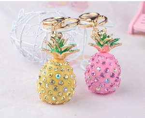 Detail of crystal pineapple keychains in pink and yellow with gold leaves and rhinestones