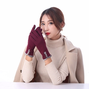 Detail of burgundy winter gloves featuring grey faux fur trim and three button accents