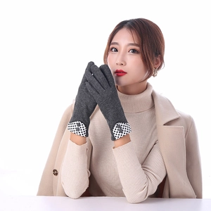 Close-up of warm dark gray knit gloves featuring checkered cuffs and decorative buttons