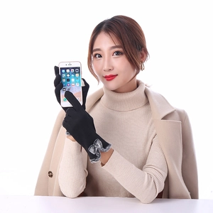 Close-up of black thermal gloves with grey faux fur bow detail and touchscreen function