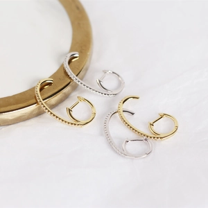 Detail of C-shaped earrings in gold and silver finish with pavé set cubic zirconia