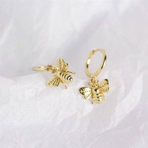 Macro shot of gold-plated bee earrings showing intricate wing textures and metal details