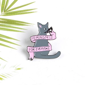 Detailed shot of grey cat enamel pin with Feminism is for Everyone ribbon slogan