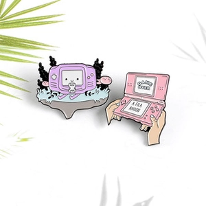 Detail shot of vintage handheld game console enamel pins in purple and pink finishes