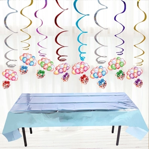 Detail of blue disposable party tablecloth with hanging metallic foil swirls and gift decors