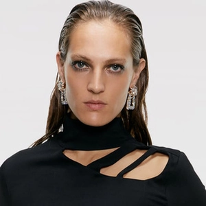 Macro shot of large rectangular earrings with sparkling rhinestones worn by a model