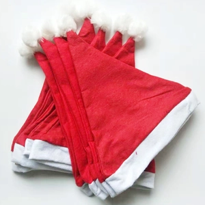 Detailed stack of red non-woven Christmas hats with white pom-poms on white background
